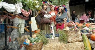 Mujeres vestidas con los trajes de la Ã©poca presiden un montaje medieval de productos de la huerta.